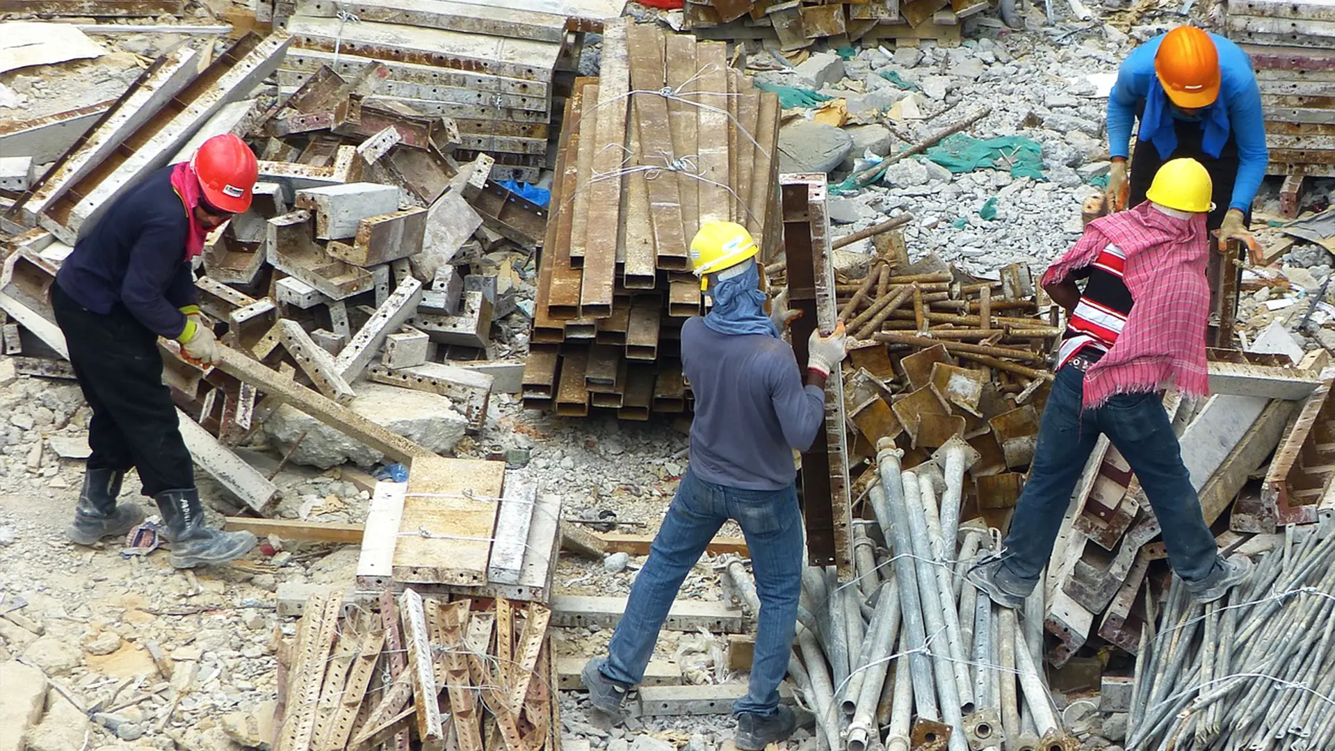 Workers sorting and lifting composite beams on a commercial job site
